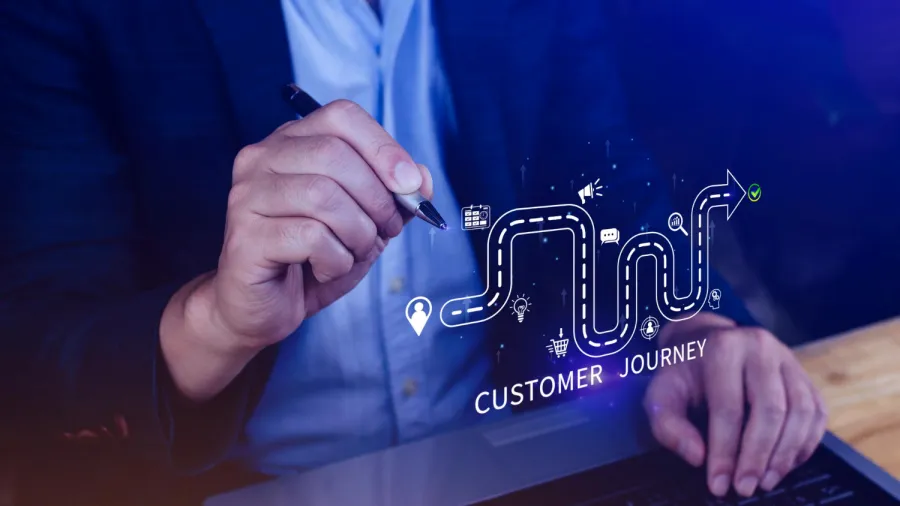 A person in a suit holding a pen draws a winding path with icons and the words Customer Journey on a virtual screen, symbolizing stages of the customer experience.